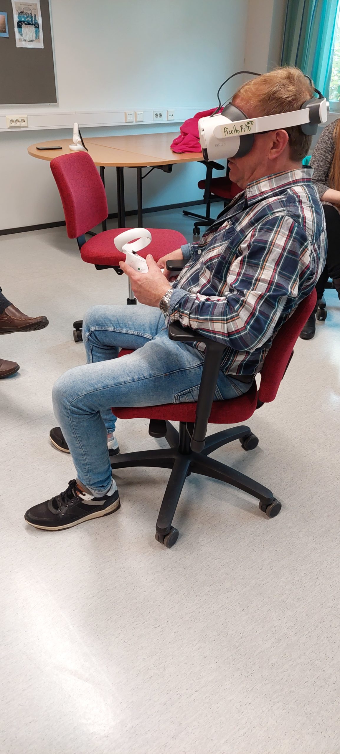 Henkilö istuu pyörivällä tuolilla ja hänellä on päässään VR-lasit.