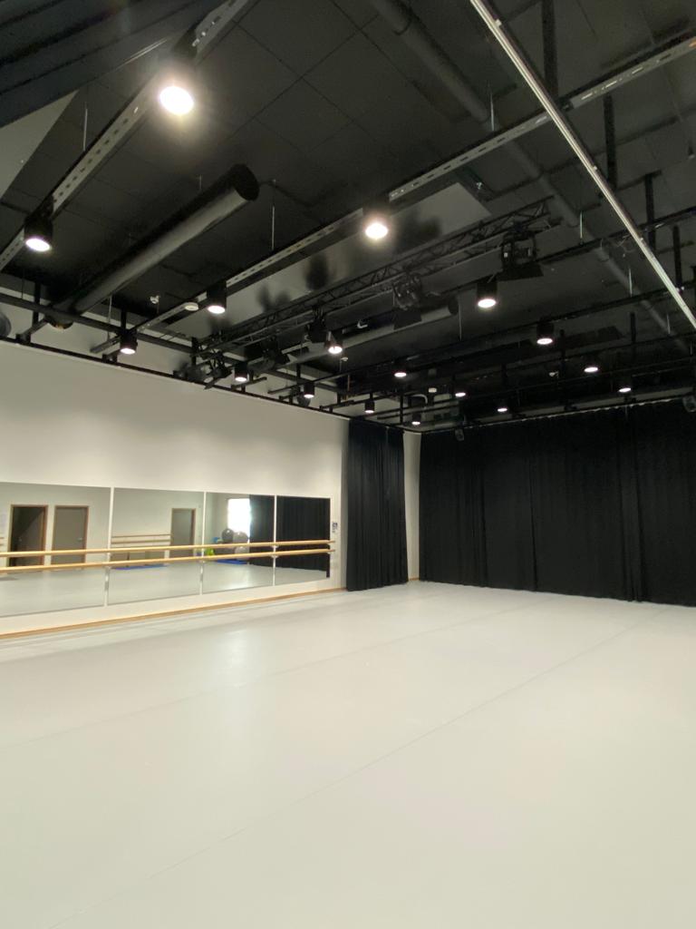 Tanssistudiosta yleiskuva. Tilassa on peilit seinällä. Mustat verhot seinustalla ja musta katto.