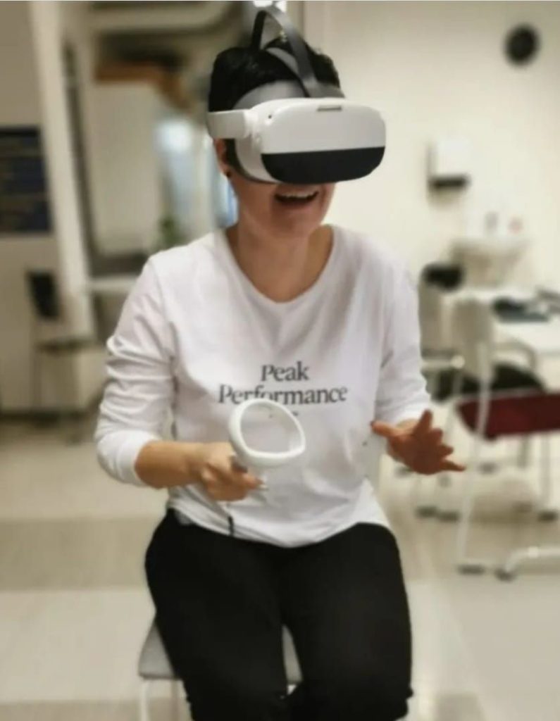 Henkilö istuu tuolilla pelaamassa VR-laseilla virtuaalisia oppimisympäristöjä.