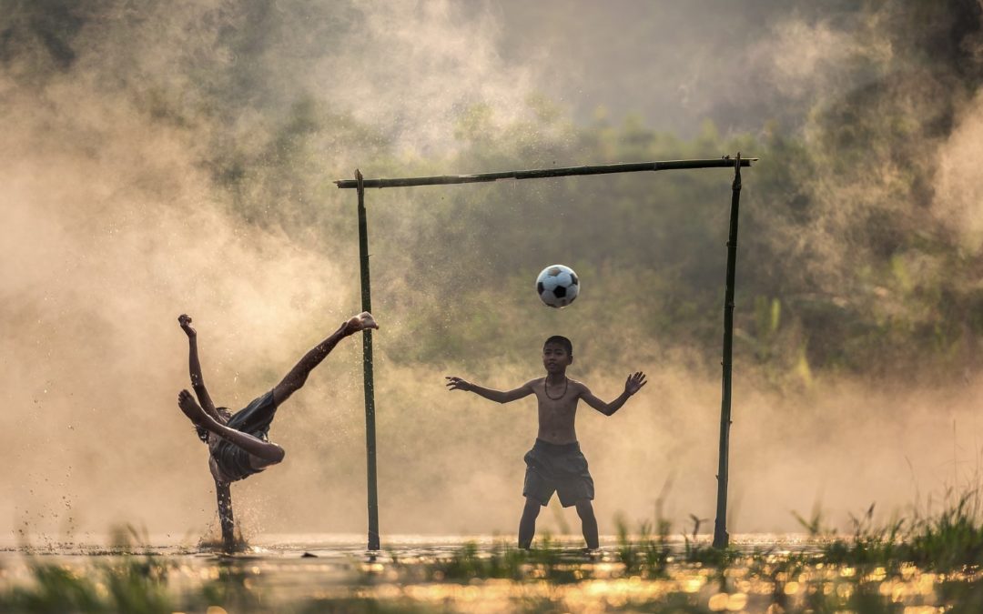 Kuvassa kaksi lasta leikkii jalkapallolla.