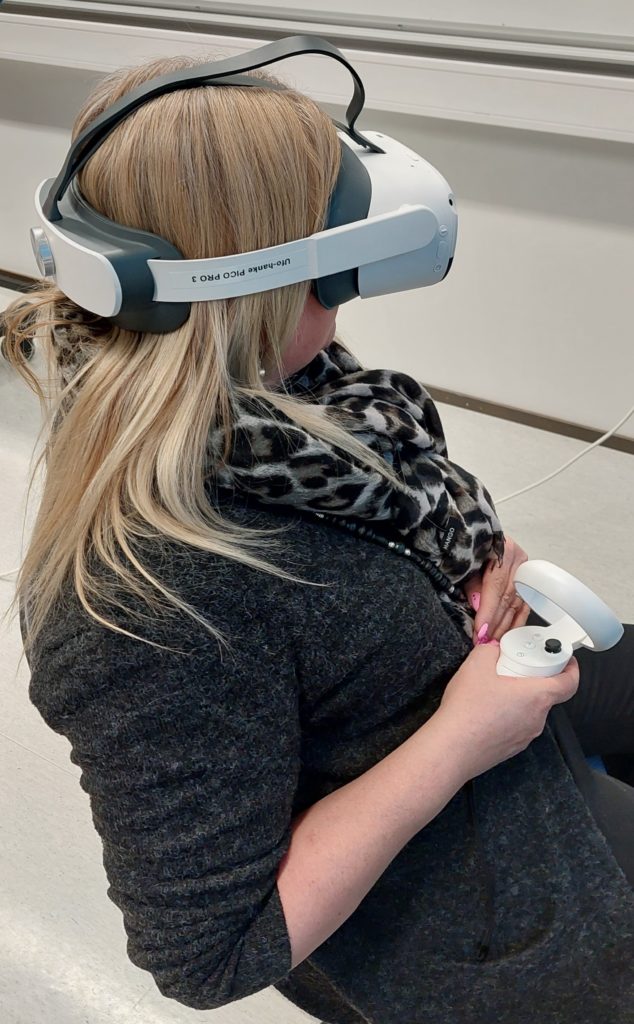 Henkilö istuu VR-lasit päässä ja kädessä on ohjain.